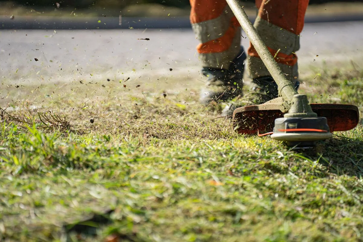 Black gardener maintaining landscaping and lawn care at a property